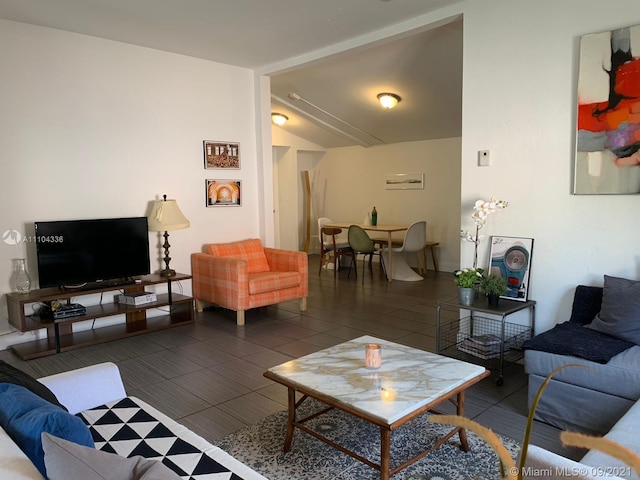 living room featuring vaulted ceiling and dark tile flooring