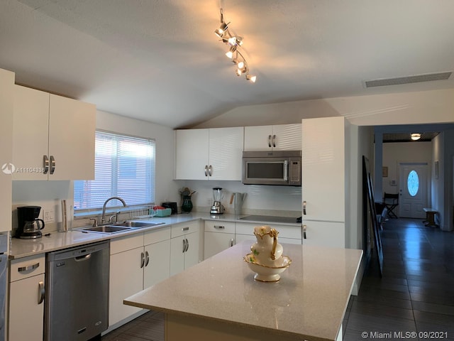 kitchen with white cabinetry, lofted ceiling, appliances with stainless steel finishes, light stone counters, and a kitchen island