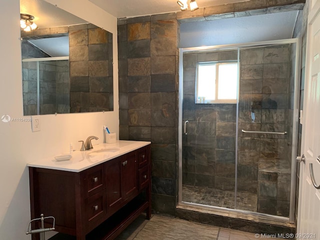 bathroom with an enclosed shower, vanity, and tile floors