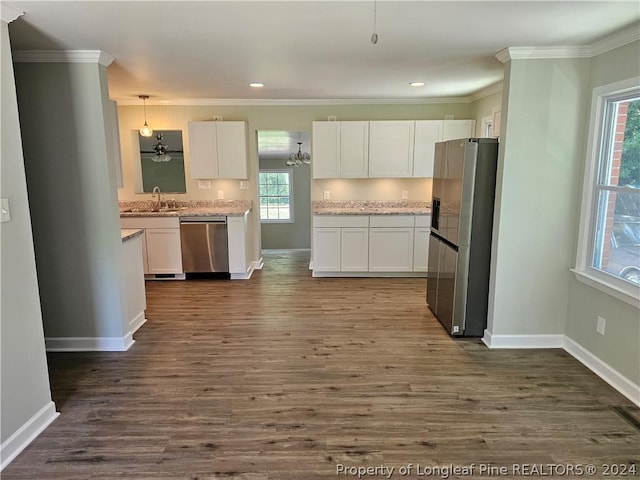 kitchen featuring white cabinets, decorative light fixtures, and stainless steel appliances