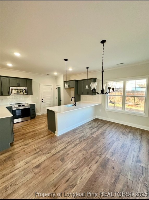 kitchen featuring decorative light fixtures, sink, ornamental molding, stainless steel appliances, and light wood-type flooring