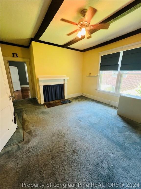 unfurnished living room featuring a fireplace, beam ceiling, carpet floors, and ceiling fan