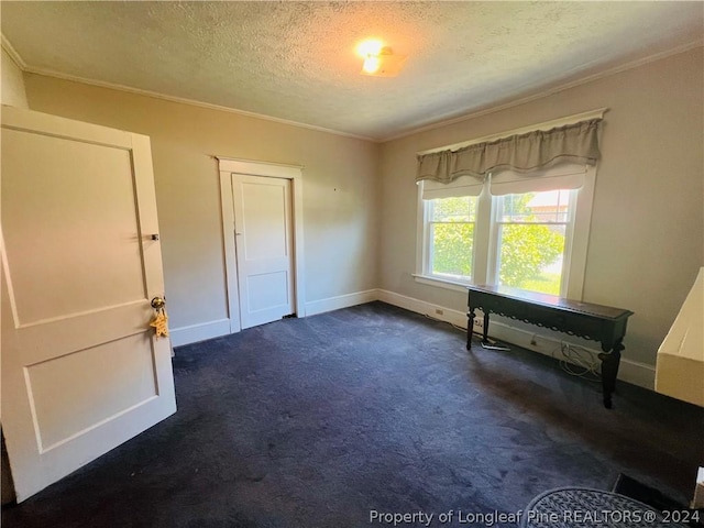 unfurnished bedroom featuring crown molding, dark carpet, and a textured ceiling