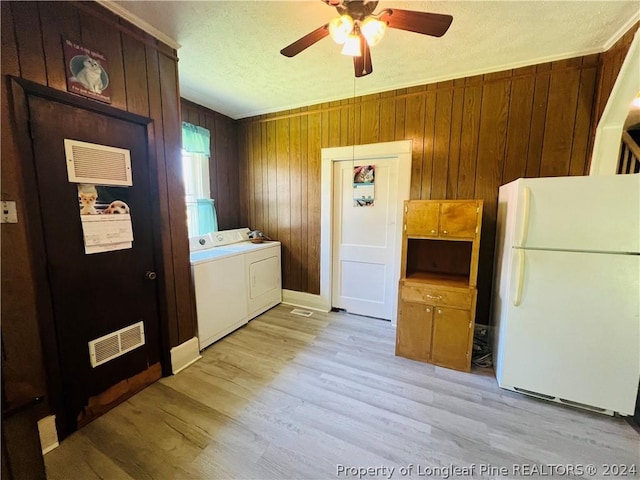 laundry room featuring light wood-type flooring, washing machine and dryer, ceiling fan, and wooden walls