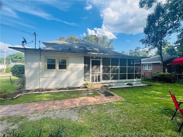 rear view of property featuring a sunroom and a yard