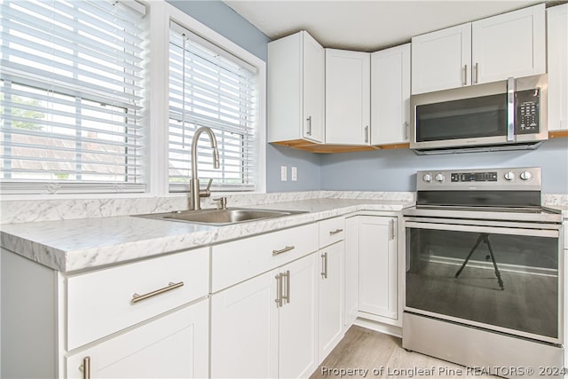 kitchen with sink, appliances with stainless steel finishes, white cabinets, and a wealth of natural light