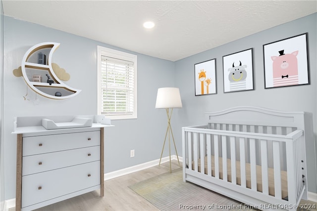 bedroom featuring a crib and light hardwood / wood-style flooring