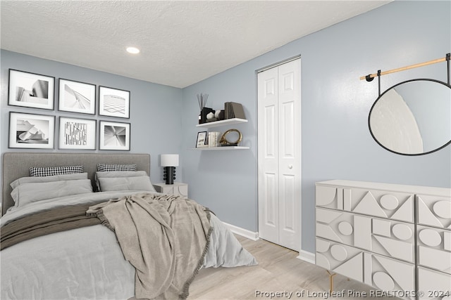 bedroom featuring light hardwood / wood-style floors, a closet, and a textured ceiling