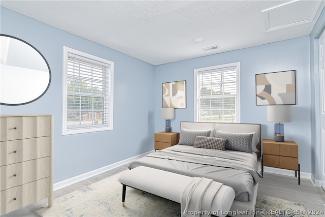 bedroom with multiple windows and light wood-type flooring