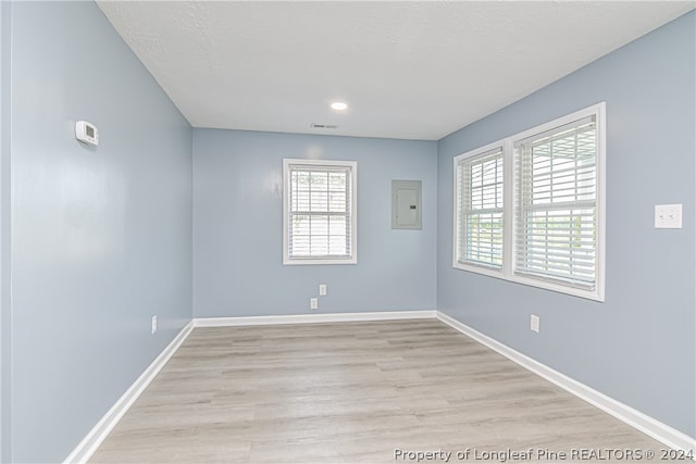 unfurnished room with electric panel and light wood-type flooring