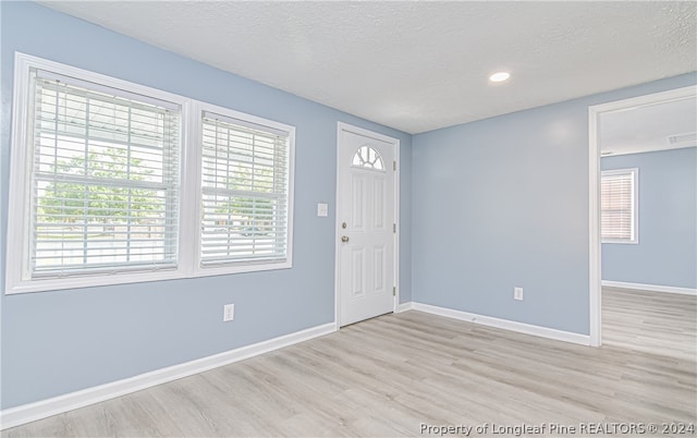 entrance foyer with light hardwood / wood-style flooring and a textured ceiling