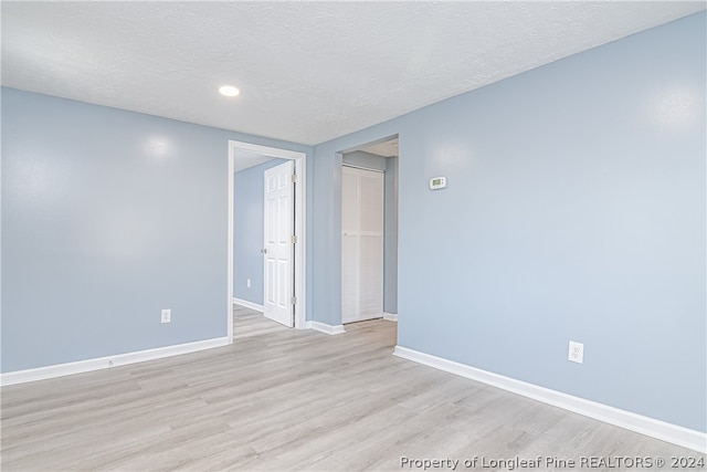 unfurnished room featuring a textured ceiling and light wood-type flooring