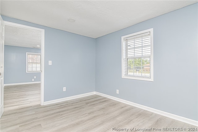 empty room with light hardwood / wood-style floors and a textured ceiling