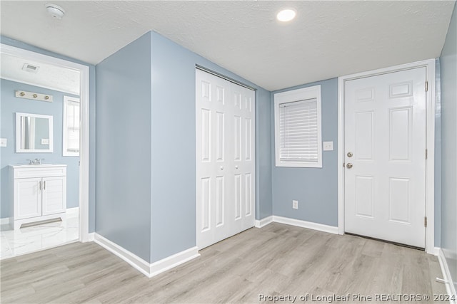 foyer with light wood-type flooring and a textured ceiling