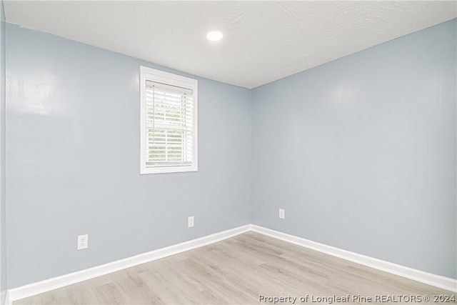 empty room featuring light wood-type flooring and a textured ceiling