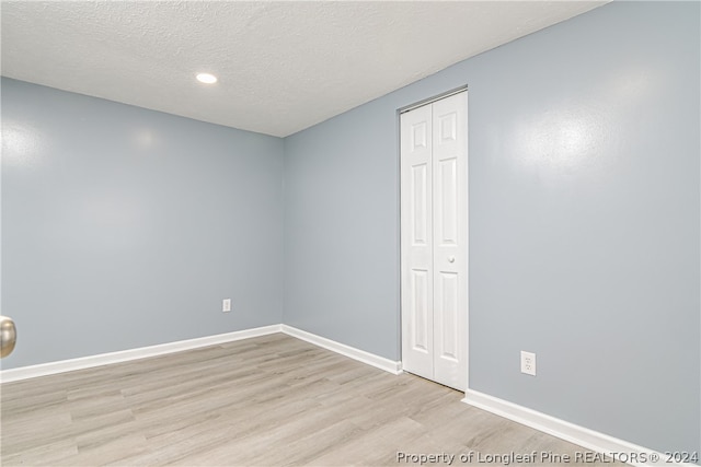 unfurnished room featuring a textured ceiling and light wood-type flooring