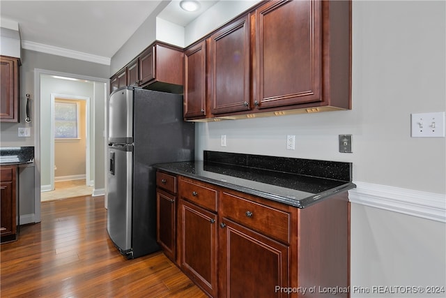 kitchen featuring crown molding, dark stone counters, stainless steel refrigerator, and dark hardwood / wood-style floors