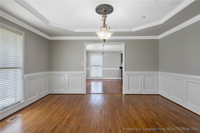 empty room featuring crown molding, a raised ceiling, a healthy amount of sunlight, and hardwood / wood-style floors