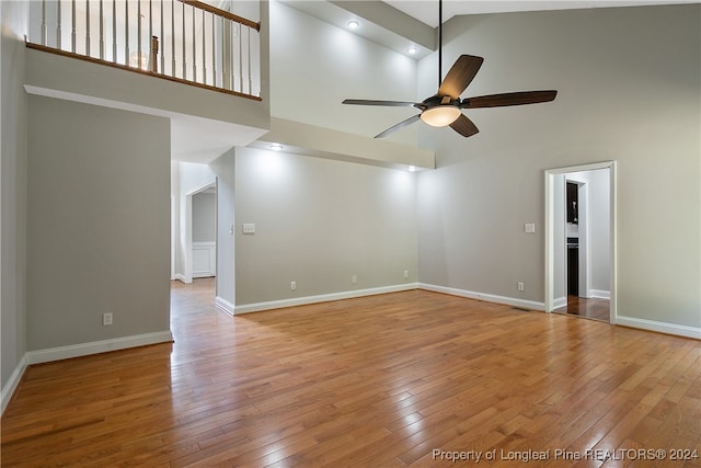 empty room with high vaulted ceiling, wood-type flooring, and ceiling fan