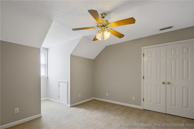 bonus room with lofted ceiling, ceiling fan, light colored carpet, and a textured ceiling