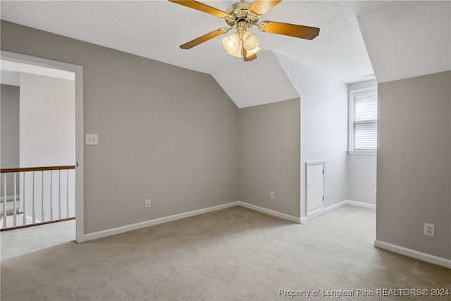 additional living space featuring ceiling fan, a textured ceiling, light carpet, and vaulted ceiling