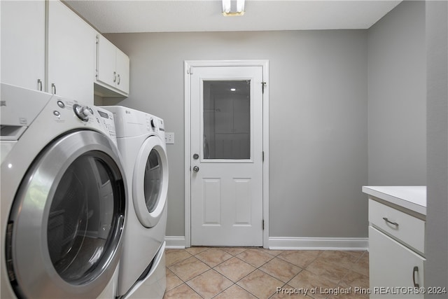 laundry room with washing machine and clothes dryer, cabinets, and light tile patterned floors