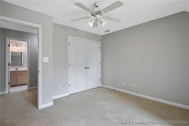 unfurnished bedroom featuring a closet, ceiling fan, light carpet, and connected bathroom