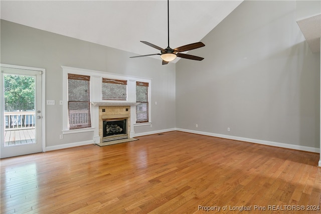 unfurnished living room featuring high vaulted ceiling, ceiling fan, a high end fireplace, and light wood-type flooring