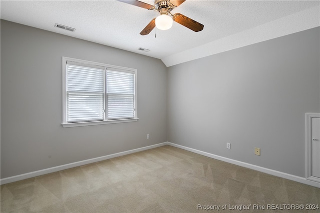 spare room featuring ceiling fan, light carpet, and a textured ceiling