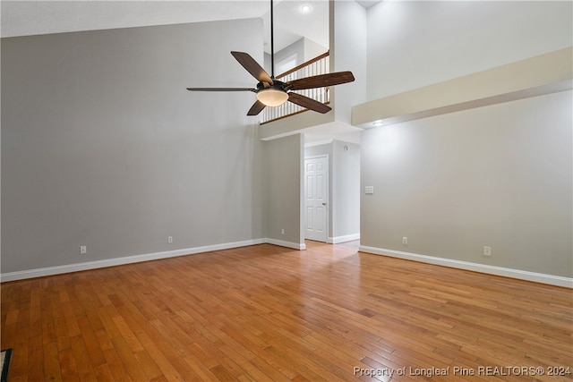 unfurnished room with ceiling fan, light wood-type flooring, and high vaulted ceiling