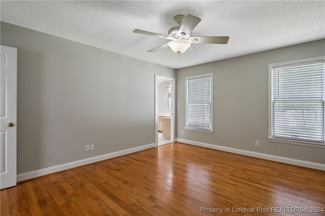 empty room featuring plenty of natural light, wood-type flooring, and ceiling fan