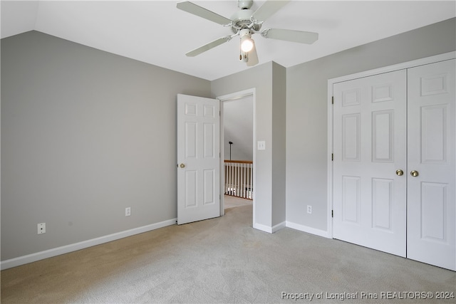 unfurnished bedroom featuring light colored carpet, ceiling fan, a closet, and vaulted ceiling