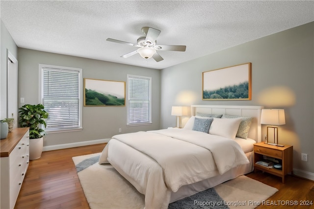 bedroom with a textured ceiling, wood-type flooring, and ceiling fan