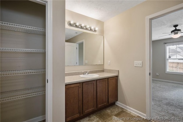 bathroom with ceiling fan, vanity, and a textured ceiling