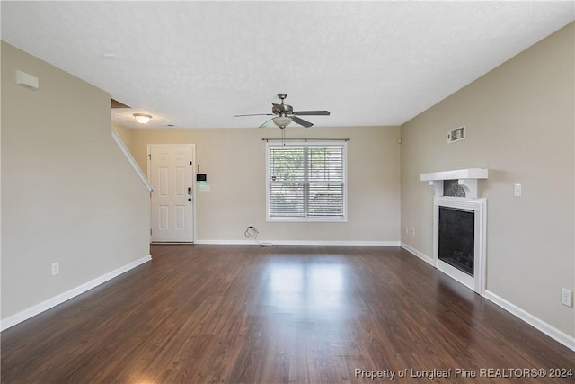 unfurnished living room with ceiling fan, dark hardwood / wood-style flooring, and a textured ceiling