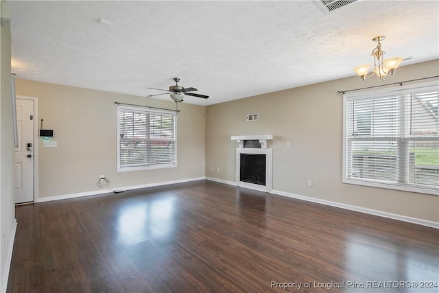 unfurnished living room with dark wood-type flooring, ceiling fan with notable chandelier, and a textured ceiling