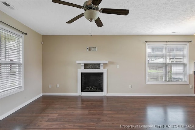 unfurnished living room featuring a healthy amount of sunlight, dark hardwood / wood-style flooring, and a textured ceiling