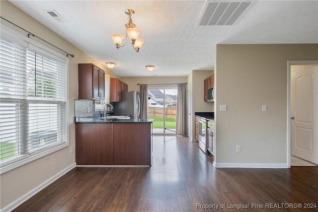 kitchen featuring dark hardwood / wood-style flooring, a notable chandelier, stainless steel appliances, and kitchen peninsula