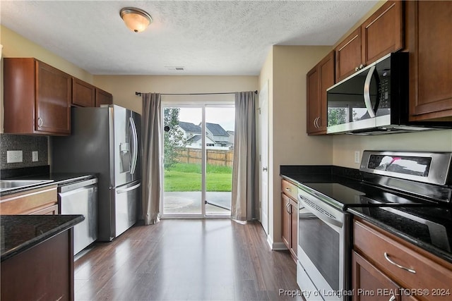 kitchen featuring dark wood-type flooring, appliances with stainless steel finishes, and dark stone countertops