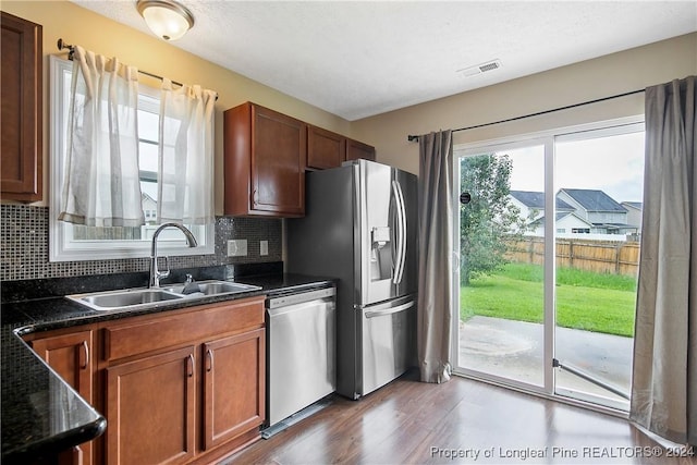 kitchen featuring sink, backsplash, stainless steel appliances, dark wood-type flooring, and a textured ceiling