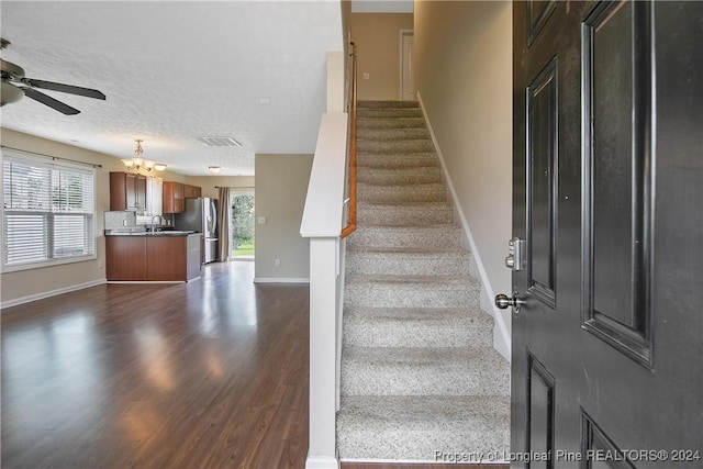 staircase featuring hardwood / wood-style flooring, sink, ceiling fan with notable chandelier, and a textured ceiling