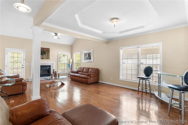 living room with hardwood / wood-style floors, a tray ceiling, ornate columns, crown molding, and ceiling fan