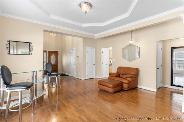 living room with ornamental molding, wood-type flooring, and a tray ceiling