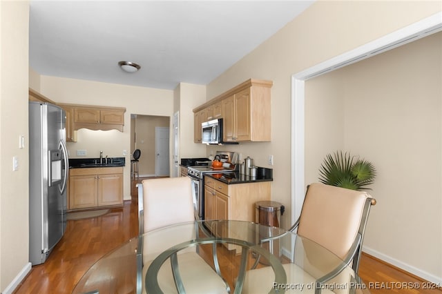 kitchen with hardwood / wood-style floors, light brown cabinetry, stainless steel appliances, and sink