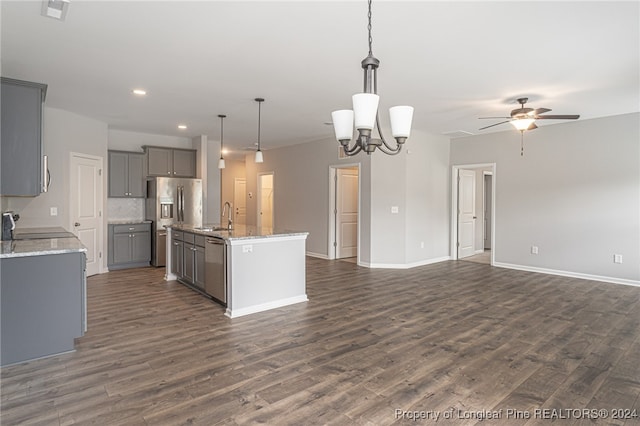 kitchen with gray cabinetry, hanging light fixtures, ceiling fan with notable chandelier, dark hardwood / wood-style floors, and a kitchen island with sink