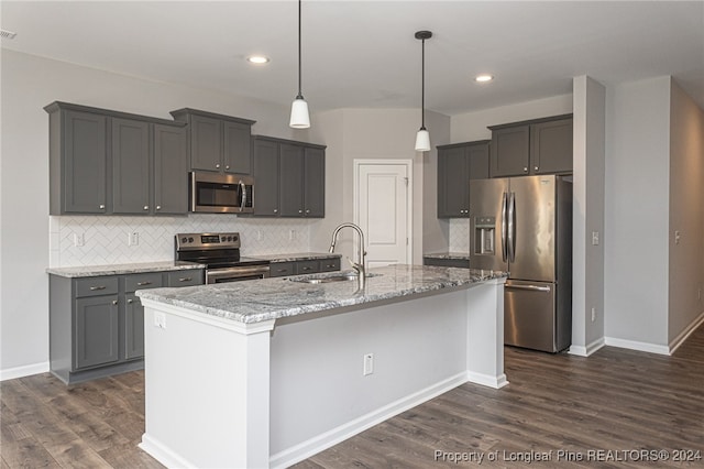 kitchen featuring light stone countertops, dark hardwood / wood-style flooring, a kitchen island with sink, stainless steel appliances, and sink