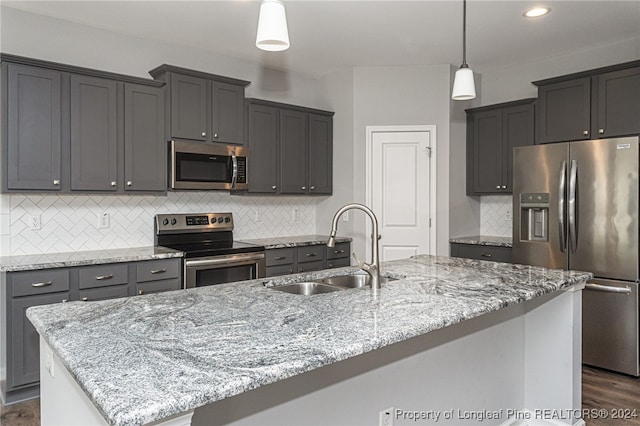 kitchen with appliances with stainless steel finishes, a center island with sink, tasteful backsplash, and sink