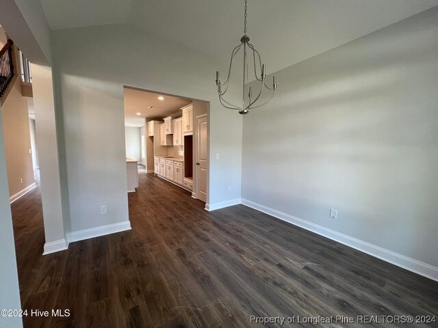 unfurnished dining area with an inviting chandelier, dark hardwood / wood-style flooring, and vaulted ceiling