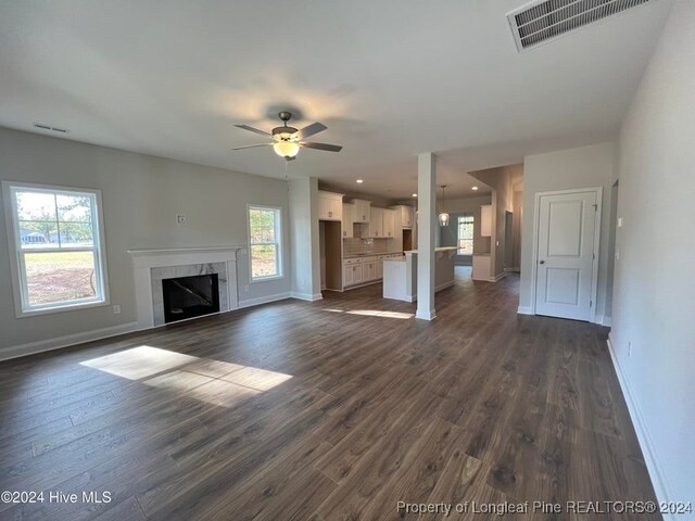 unfurnished living room featuring a fireplace, dark hardwood / wood-style flooring, and a healthy amount of sunlight