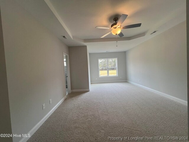 carpeted empty room featuring a raised ceiling and ceiling fan